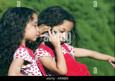 Zwillingsschwestern telefonieren mit Handy Stockfoto