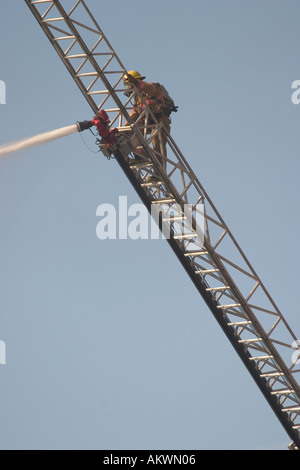 Wasser gesprüht auf einem großen industriellen Feuer durch ein Feuerwehrmann von einem Boom-Leiter Stockfoto