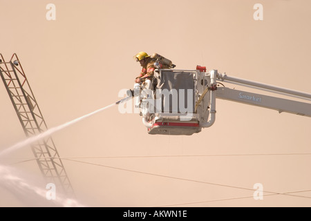 Wasser gesprüht auf einem großen industriellen Feuer durch ein Feuerwehrmann von einem Schnorchel-boom Stockfoto