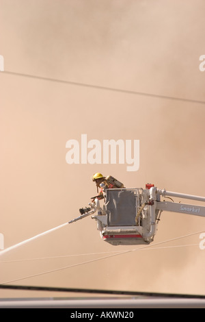 Wasser gesprüht auf einem großen industriellen Feuer durch ein Feuerwehrmann von einem Schnorchel-boom Stockfoto