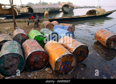 Farbige Metall Fässer verwendet, waren im Fluss Transport tragen sitzen am Ufer des Flusses Niger in Mopti Mali verschmutzten Stockfoto