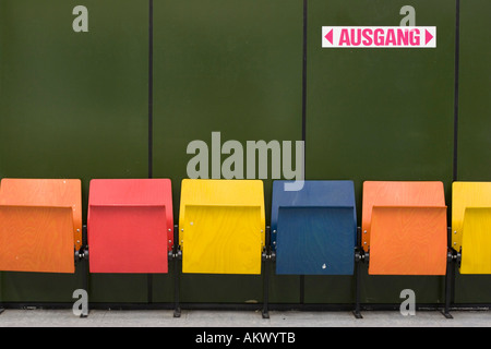 Bunte Sitze vor einer grünen Wand mit 'Exit'-Zeichen Stockfoto