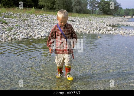 Kleiner Junge, vier-jährige, Wandern mit Gummistiefeln durchs Wasser, Fluss Isar bei München, Germany Stockfoto