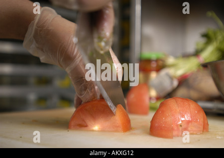 Ein Köche Hände, eine Tomate würfeln. Stockfoto