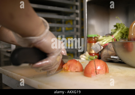 Ein Köche Hände, eine Tomate würfeln. Stockfoto