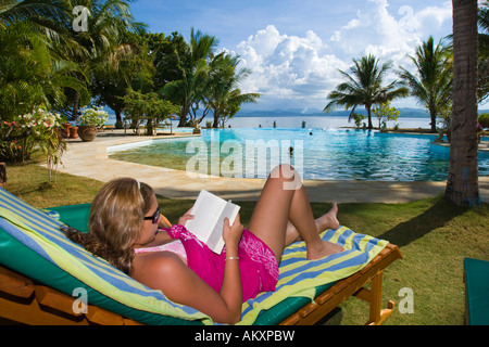 Gangga Island den Pool-Bereich. Eine Frau liest ein Buch, Insel mit einem Hotel im Norden von Sulawesi, Indonesien. Stockfoto