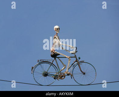 Skelett mit dem Fahrrad auf einem Drahtseil Stockfoto