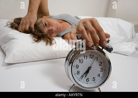 Frau im Bett, Wecker ausschalten Stockfoto