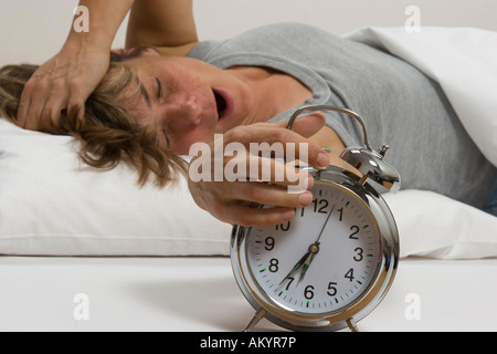 Frau im Bett, Wecker ausschalten Stockfoto