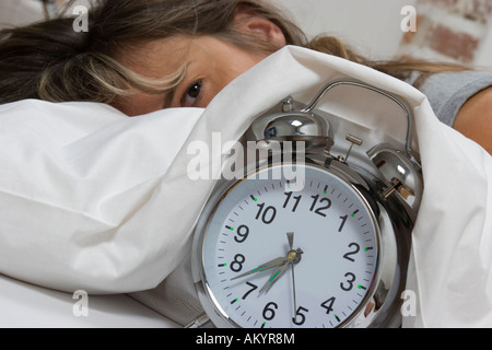 Frau im Bett, Wecker Stockfoto