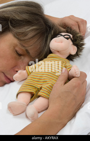 Frau mit einer Puppe im Bett Stockfoto