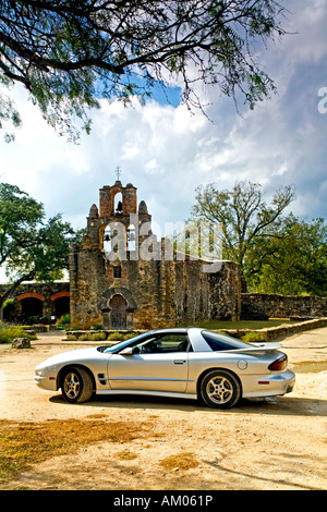 Mission Espada und Trans Am Sportwagen geparkt vor unter Baum Stockfoto