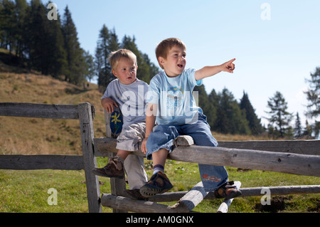 Zwei Jungs sitzen auf einem Zaun, Kärnten, Österreich Stockfoto