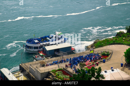 Touristen, die an Bord der Maid of the Mist Bootstour bei Niagarafällen, Ontario, Kanada, gehen und die berühmte Aussicht auf die berühmten Wasserfälle genießen. Stockfoto