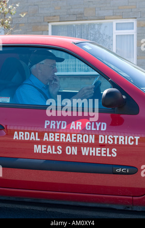 männliche Fahrer in einem Auto liefern Essen auf Rädern-Service Aberaeron Ceredigion Wales UK Stockfoto