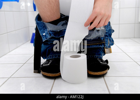 Mann sitzt auf Toilette Stockfoto