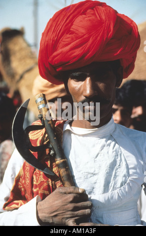 Indischen Rajasthan Wüste tribal Mann mit wunderschön gebundenen roten Turban und eine Axt. Stockfoto