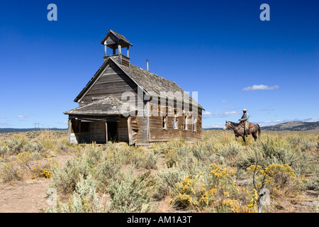 Cowboy mit Pferd am alten Schulhaus, Wildwest, Oregon, USA Stockfoto