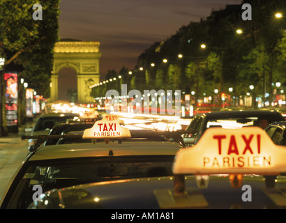 Taxis und Verkehr in der Nacht auf der Champs-Elysées mit dem Arc de Triomphe in Paris Stockfoto