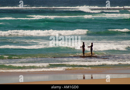 Zwei Fischer stehen in den Wellen am Tofo Beach. Mosambik, Südafrika Stockfoto