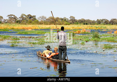 Einheimische mit Touristen im Mokoro-Dugoutboat in das Okavango Delta, Botswana Stockfoto