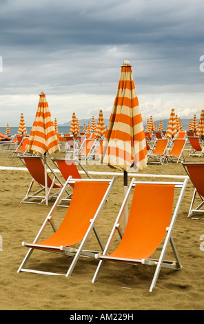 Orangefarbene Liegestühle an einem einsamen Strand in Viareggio Italien Stockfoto