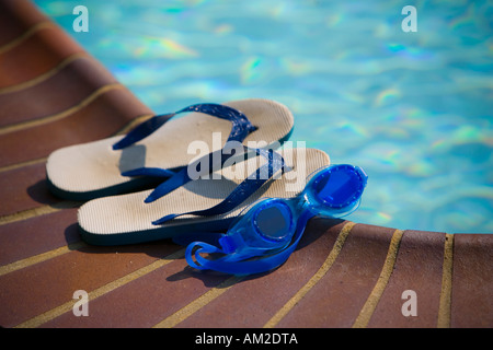 Schutzbrillen und Flip Flops an der Seite eines Pools Stockfoto