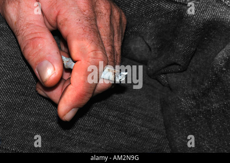 Ein Mans Hand Holding eine ungefilterte Rollup beleuchtete Zigarette Stockfoto