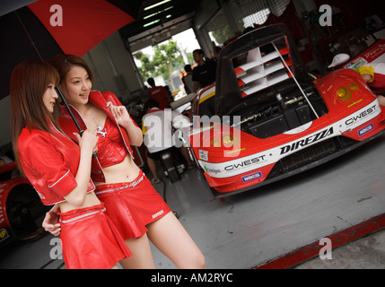 Japanische Modelle posieren vor einem JapanGT-Sportwagen auf dem Sepang International Circuit, Malaysia Stockfoto