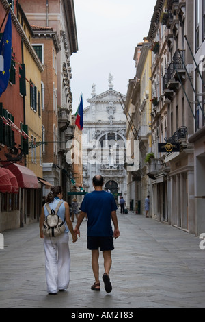 Paar halten Hände Spaziergänge entlang der Calle Larga XXII Marzo mit San Moise Kirche in Ferne Venedig Italien Stockfoto