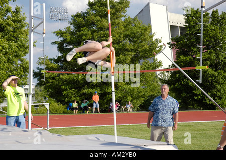 Teenager-Mädchen Stabhochspringer clearing der Bar an einer High School Leichtathletik Bezirk treffen Stockfoto