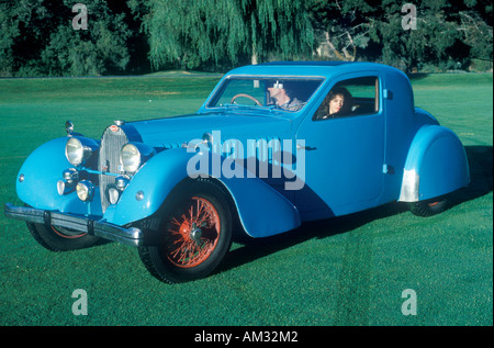 Ein Mann und eine Frau sitzen in einem blauen Bugatti Auto bei einer Oldtimer-Show in Pebble Beach Kalifornien ca 1985 Stockfoto