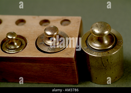 Drei französische Kupfer Waage Gewichte in einer Holzkiste ausgerichtet Stockfoto