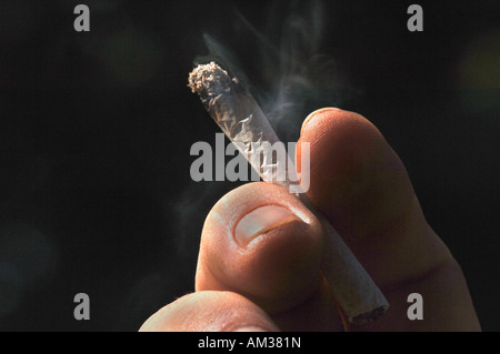 Ein Mans Hand Holding eine ungefilterte Rollup beleuchtete Zigarette Stockfoto