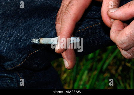 Ein Mans Hand Holding eine ungefilterte Rollup beleuchtete Zigarette Stockfoto