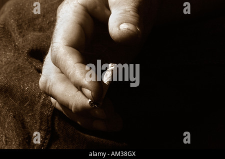 Ein Mans Hand Holding eine ungefilterte Rollup beleuchtete Zigarette Stockfoto