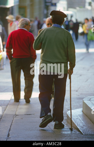 Ältere Männer zu Fuß entlang einer belebten Straße in Segovia Castilla y Leon Spanien ein Mann geht mit einem Stock und trägt eine Baskenmütze Stockfoto