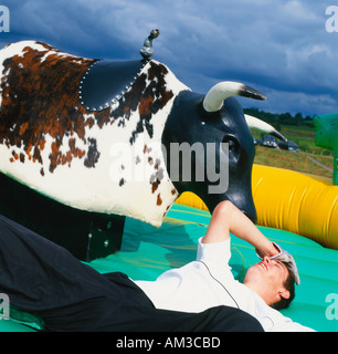 Mann auf aufblasbare gefallen, beim Reiten eines Kunststoff Stiers Llanwrtyd Wells Powys Wales UK Stockfoto