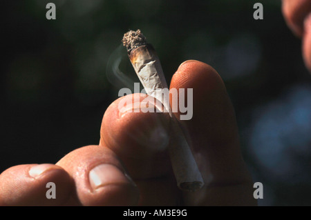 Ein Mans Hand Holding eine ungefilterte Rollup beleuchtete Zigarette Stockfoto