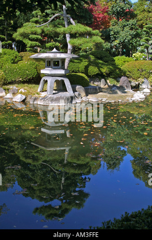 Traditionelle japanische Stein Garten Laterne spiegelt sich in ein beliebtes Touristenziel, coy Karpfen Teich See Burg von Osaka, Kansai Stockfoto