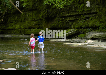 Jungen und Mädchen Hand in Hand und in einem Bach waten Stockfoto