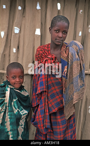 Masai Kinder verpackt in bunten Textilien stehen außerhalb ihrer Schlamm und Holz nach Hause N Arusha auf dem Weg nach S-Kenia-Tansania Stockfoto