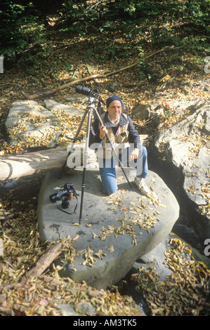 Fotograf Joe Sohm posiert auf Felsen mit seiner Kamera in Neuengland im Herbst Stockfoto