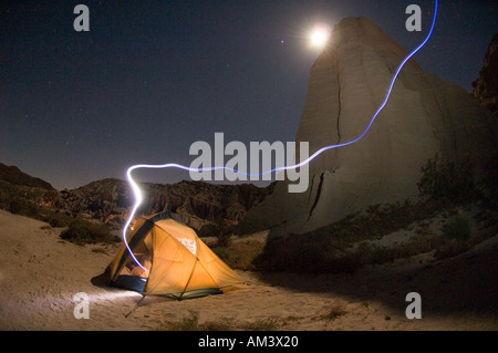 Wüste-Campingplatz mit Zelt durch Mond und Spuren der Scheinwerfer nachts beleuchtet, Red Rock Canyon state Erholungsgebiet California Stockfoto