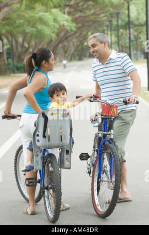 Seitenansicht eines Mitte Erwachsenen Paares miteinander zu reden, mit ihrem Sohn mit dem Fahrrad Stockfoto