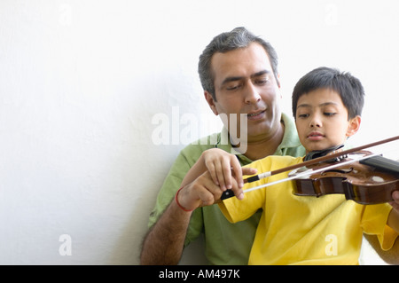 Mitte erwachsener Mann beizubringen seinen Sohn, wie man eine Geige zu spielen Stockfoto