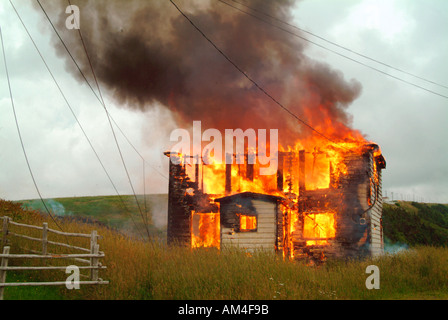 Ein kleines Haus auf den Boden in ein Feuer brennen Stockfoto