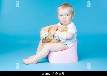 kleiner Junge mit Teddy Bär auf Toilette sitzen Stockfoto