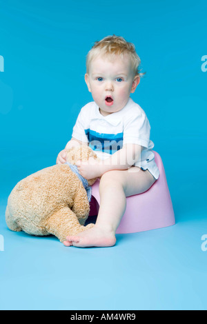 kleiner Junge mit Teddy Bär auf Toilette sitzen Stockfoto