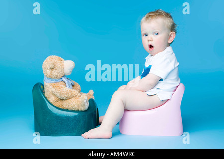 kleiner Junge mit Teddy Bär auf Toilette sitzen Stockfoto